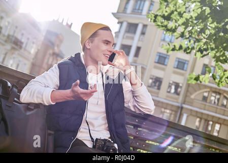 Young stylish tourist blogger is using phone on the bench. Close-up Stock Photo