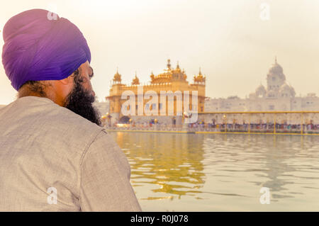 Unidentifiable Punjabi Sikh pilgrim devotee 'Nihang Warrior' sitting by the pool and meditating in front of Golden Temple ('Harmandir Sahib Darbar Gur Stock Photo