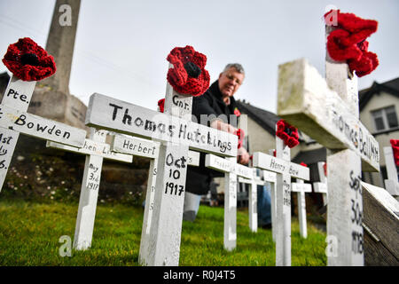 Local councillor Laurence Green tends to hand-made wooden crosses and hand-knitted poppies, which are placed on the war memorial in the Devonshire village of Ashprington, where he has adorned the small memorial with crosses of those that died in the Great War from the Ashprington Parish. Villagers tend the memorial and have made a book featuring details of parishioners that served and died during the First World War. Stock Photo