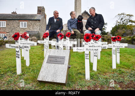 Ashprington residents (left to right) Stuart Greaves, Allan Woollacott and Laurence Green, sit alongside hand-made wooden crosses and hand-knitted poppies at the war memorial in the Devonshire village of Ashprington. Villagers tend the memorial and have made a memorial book featuring details of local parishioners that served and died during First World War. Stock Photo