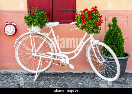 White Color Bicycle And Flower Basket Parked On Old City Street