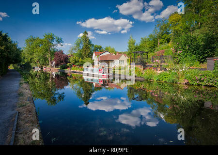 A house with a garden and a houseboat on a sunny day on Grand Union Canal, United Kingdom Stock Photo