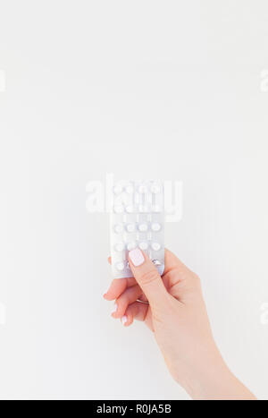 Woman hand with pastel manicure polish holding pills in blister isolated on white background with copy space. Template for feminine beauty blog social
