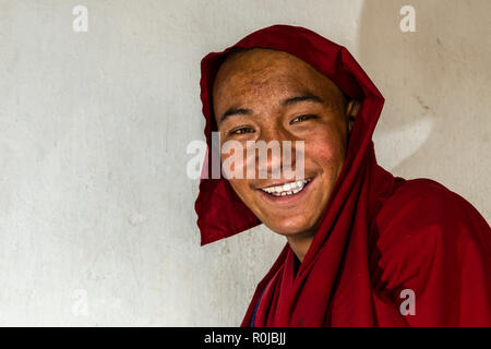 A portrait of a monk from Likir Gompa, one of the buddhist monasteries in Ladakh, dressed in red cloths and smiling. Stock Photo