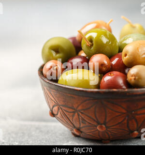 Mixed marinated olives (green and purple) in ceramic bowl. Selective focus. Square picture Stock Photo