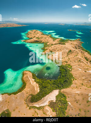 Bays, savanna lands, ocean. Komodo. Aerial view. Spectacular panorama above the stunning bays and savanna territory of Komodo National Park. Indonesia. Heritage Site. Overview drone shot. Stock Photo