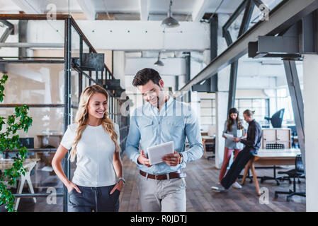 smiling young business colleagues using digital tablet at workspace Stock Photo