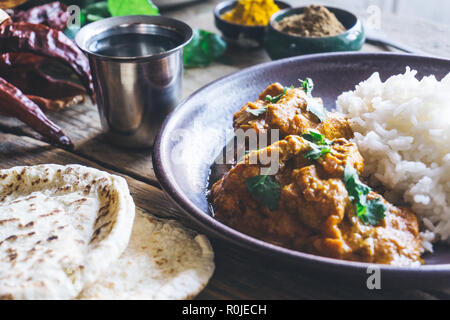 Chicken Tikka Masala (traditional indian curry) with rice and indian bread chapati decorated with spicy red chili peppers, cilantro, Indian spices (tu Stock Photo