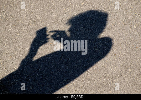 Shadow of a person using a smartphone with bad posture Stock Photo