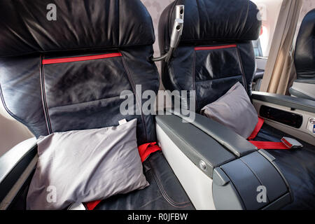 Spacious business class empty seats with pillows on a commercial flight airplane Stock Photo
