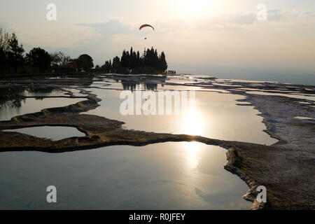 Person paragliding over the mineral pools of Pamukkale cotton castle, Turkey Stock Photo