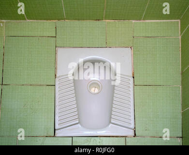 Hole in the ground squat toilet at a public restroom Stock Photo