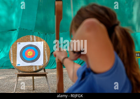 Rear view of a woman shooting an arrow with a bow at an archery target Stock Photo