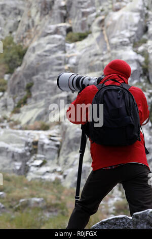 Rear view of a nature wildlife professional photographer using a Canon 200-400mm f4 super tele photo zoom lens outdoors Stock Photo