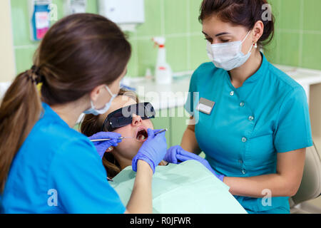 Beautiful young woman having dental treatment at dentist's office. female dentist with assistant close up Stock Photo