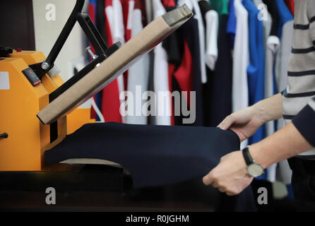Man preparing t-shirt for printing in the silk screen printing machine. Hands Stock Photo