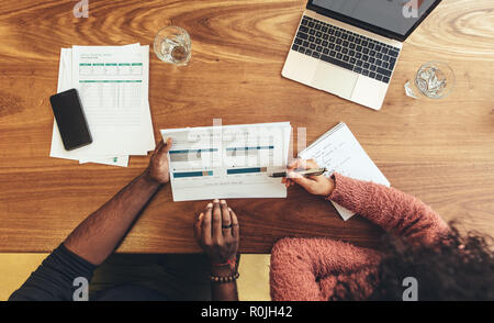 businessman and woman sitting in office discussing work using business papers. business coworkers sitting at work desk with business papers and laptop Stock Photo