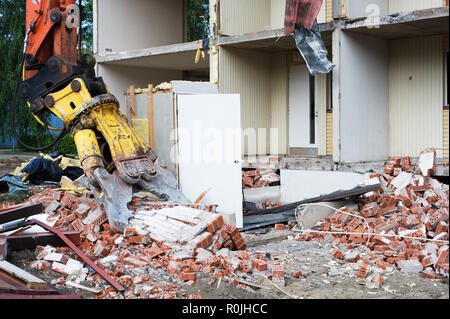 Demolition excavator crushing brick wall. Stock Photo