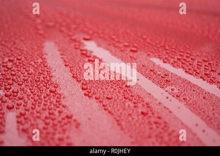 Closeup waterdrops on red ceramic coated paint surface, shallow focus Stock Photo
