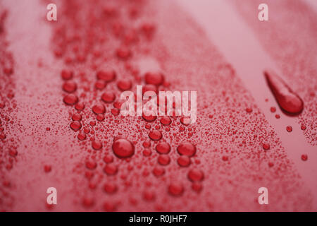 Closeup waterdrops on red ceramic coated paint surface, shallow focus Stock Photo