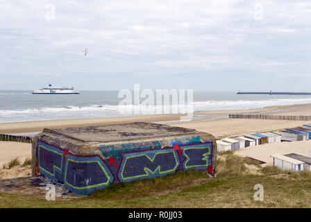 An English Channel ferry sails past remains of World War 2 German concrete bunkers on Bleriot Plage (Bleriot beach), at Sangatte, France.