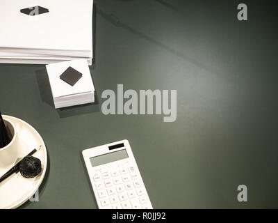 Dark office desk with white calculator, notes and other supplies Stock Photo