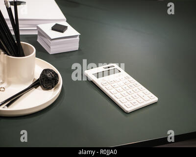 Dark office desk with white calculator, notes and other supplies Stock Photo