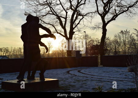 Timeline of the rising sun during the winter dusk sky viewed from behind the Bronze sculpture in the military cemetery Reimsbach an der Saar, Germany. Stock Photo