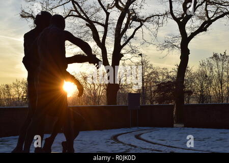 Timeline of the rising sun during the winter dusk sky viewed from behind the Bronze sculpture in the military cemetery Reimsbach an der Saar, Germany. Stock Photo