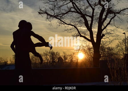 Timeline of the rising sun during the winter dusk sky viewed from behind the Bronze sculpture in the military cemetery Reimsbach an der Saar, Germany. Stock Photo