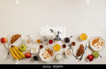 Breakfast time. Croissants and orange juice, jam and honey. Coffee with cream or milk. Fruits - bananas, red and green apples. Ricotta with sour cream Stock Photo
