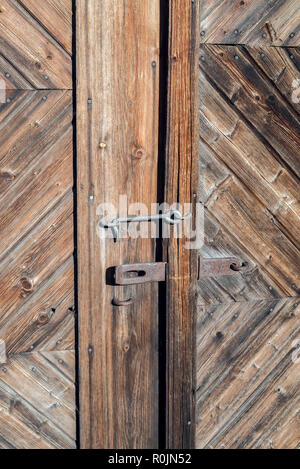 Closeup of an old rusted lock on a rustic rural door with decorative natural weathered wood planks with antique varnish - Vintage aged wooden barn Stock Photo