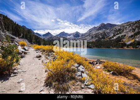 Little Lakes Valley hiking trail on a sunny fall day, following the shoreline of Long Lake in the Eastern Sierras; John Muir Wilderness; California Stock Photo