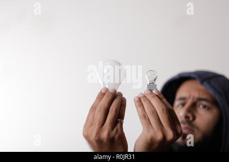 An engineer comparing two different light bulbs Stock Photo