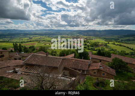 The Beaujolais wine growing landscape in France nestles under a dramatic cloudy sky, as viewed from the top of small picturesque village of Oingt. Stock Photo