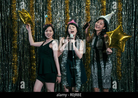 young ladies singing and dancing on the stage in the bar. girl dancer and singer having performance enjoyment. women with beer microphone and star bal Stock Photo