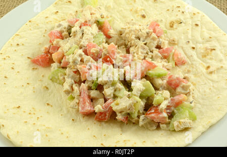 Close up of chopped chicken, cucumbers, tomatoes with sour cream on tortilla on plate for making chicken wrap Stock Photo