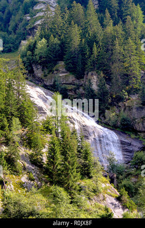 Beautiful waterfall in the mountain surrounded by pine trees. Stock Photo