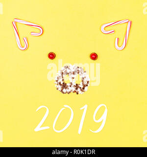 Christmas pig face made of candy cane lollipops and golden confetti on yellow background. Concept of animal 2019. Stock Photo
