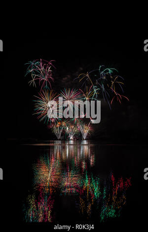 Red, green and yellow stars from rich fireworks over Brno's Dam with lake reflection Stock Photo