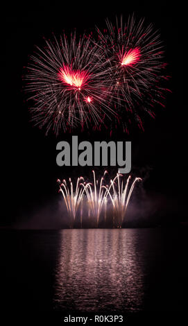 Red stars and gold fountain from rich fireworks over Brno's Dam with lake reflection Stock Photo