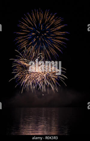 Big gold and blue stars from fireworks over Brno's Dam with lake reflection Stock Photo