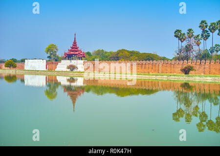 The walls with towers and lush park behind, the only elements of Royal Palace that seen from city streets, Mandalay, Myanmar Stock Photo