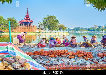 MANDALAY, MYANMAR - FEBRUARY 23, 2018: Burmese women during manual construction works on embankment of the Citadel's moat, on February 23 in Mandalay. Stock Photo