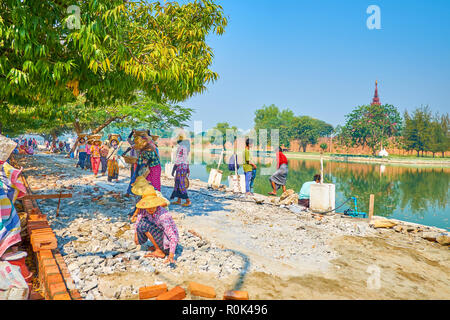 MANDALAY, MYANMAR - FEBRUARY 23, 2018: The road repairing process with manual stone carrying and paving the promenade of Royal Palace, on February 23  Stock Photo