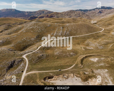 Rural road in unspoiled hills and steppe in Bosnia. Aerial drone view Stock Photo