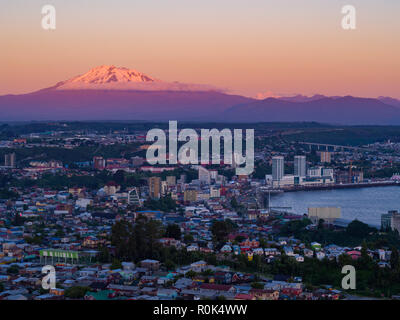 Aerial view of the city of Puerto Montt at dusk, the Osorno and Calbuco volcanoes are visible in the background Stock Photo