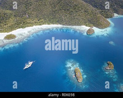 A Pinisi schooner sits at anchor in a remote area of Raja Ampat in eastern Indonesia. Stock Photo