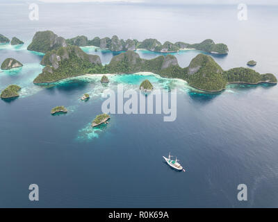 A Pinisi schooner sits at anchor in a remote area of Raja Ampat in eastern Indonesia. Stock Photo