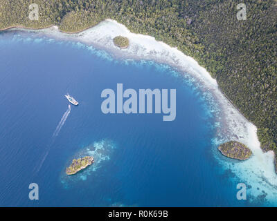 A Pinisi schooner sits at anchor in a remote area of Raja Ampat in eastern Indonesia. Stock Photo